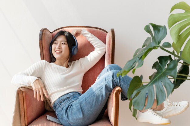 Free Photo asian woman listening to music on a red sofa