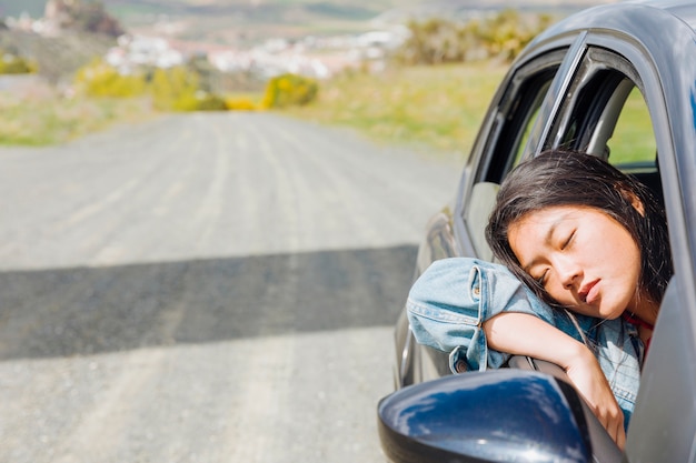 Asian woman napping in car during roadtrip 