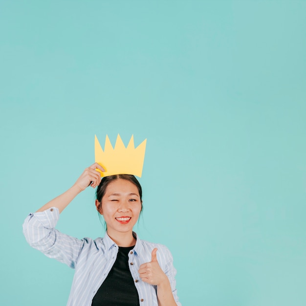 Free photo asian woman in paper crown gesturing thumb-up