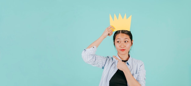 Asian woman in paper crown pointing left