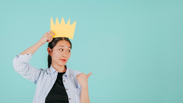 Free photo asian woman in paper crown pointing right