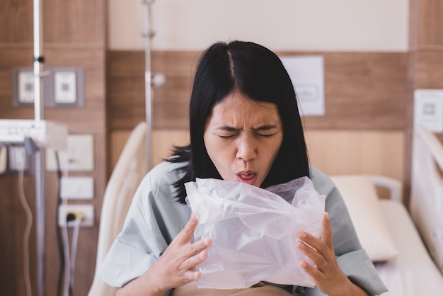 아시아 여성 환자가 병원에서 비닐 봉지에 토하거나 구토, 메스꺼움, 소화불량