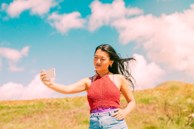 Asian woman photographing in field