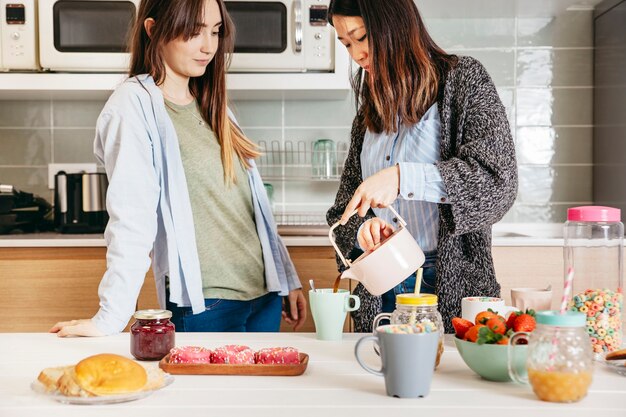 Asian woman pouring tea for friend