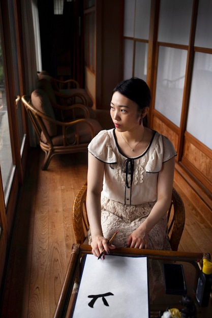 Asian woman practicing japanese handwriting indoors