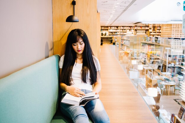 Азиатская женщина читает в книжном магазине