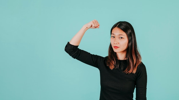 Foto gratuita donna asiatica che mostra il muscolo