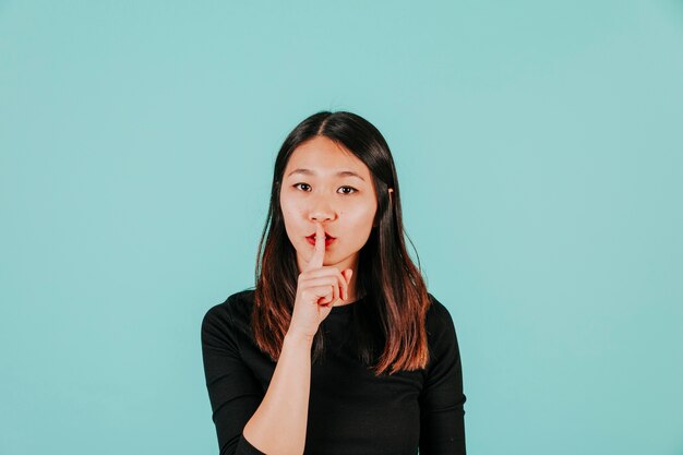 Asian woman showing silence gesture
