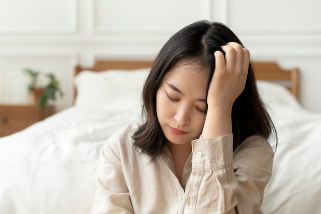 Asian woman sitting sad by her bed Free Photo