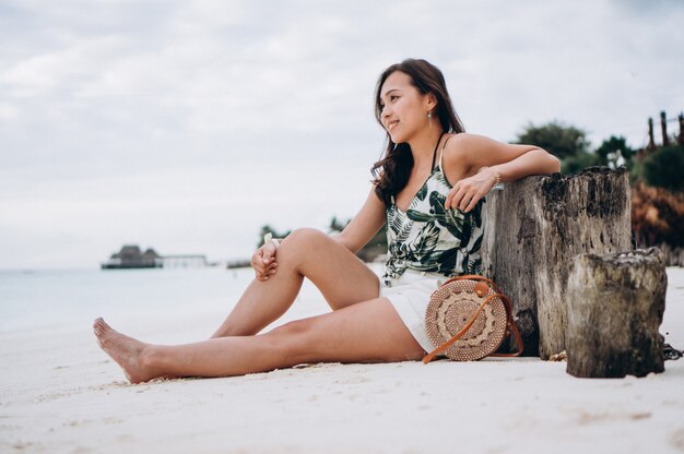Asian woman sitting on white sand by the indian ocean