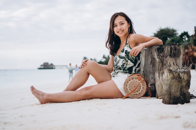 Asian woman sitting on white sand by the indian ocean