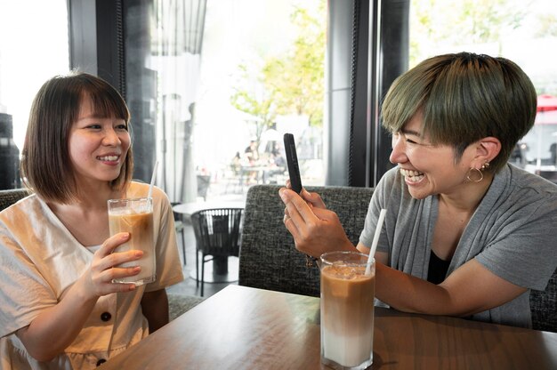 彼女の携帯電話で彼女の友人の写真を撮るアジアの女性