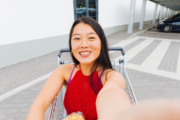 Asian woman taking selfie in shopping trolley