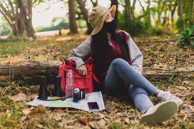 座って休んでいるフェイスマスクを着たアジアの女性観光客。