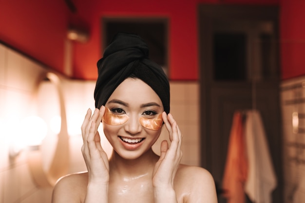 彼女の頭の上のタオルでアジアの女性は顔のマッサージをします