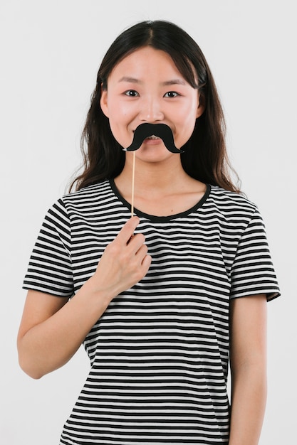 Foto gratuita donna asiatica che prova i baffi falsi