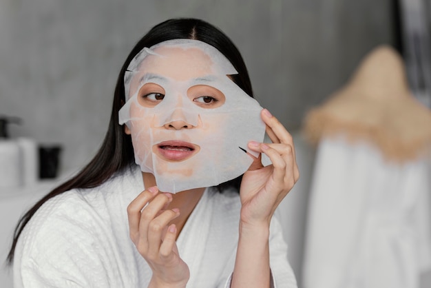 Бесплатное фото Азиатская женщина, использующая маску листа