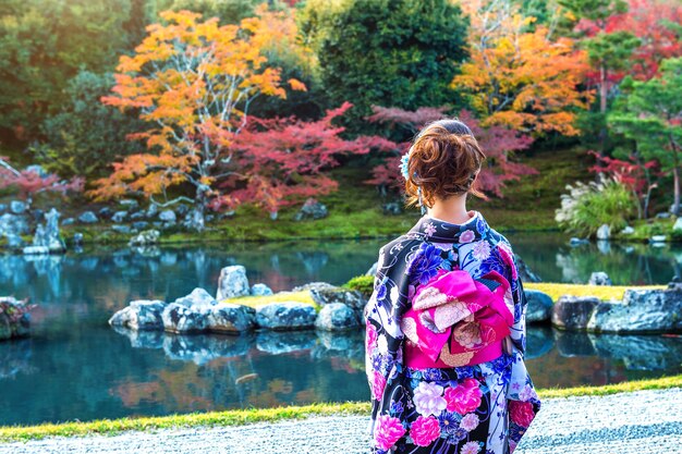 秋の公園で日本の伝統的な着物を着ているアジアの女性。日本