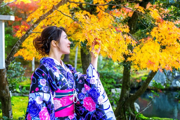 秋の公園で日本の伝統的な着物を着ているアジアの女性。日本
