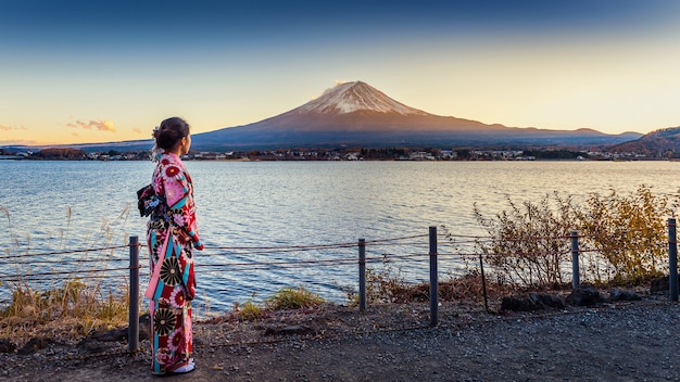 Donna asiatica che indossa il kimono tradizionale giapponese al monte fuji. tramonto al lago kawaguchiko in giappone.