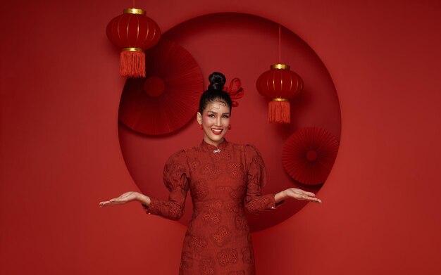 Asian woman wearing traditional cheongsam qipao dress with gesture of welcome chinese new year 2024