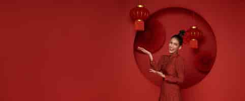 Foto gratuita donna asiatica che indossa il tradizionale cheongsam qipao con il gesto di benvenuto al nuovo anno cinese 2024