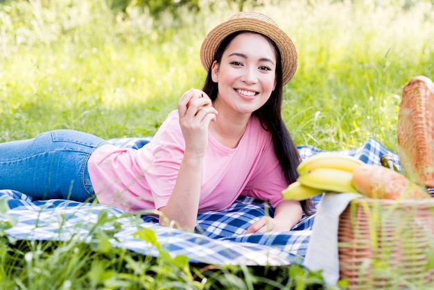 Азиатская женщина с яблоком, лежа на одеяле