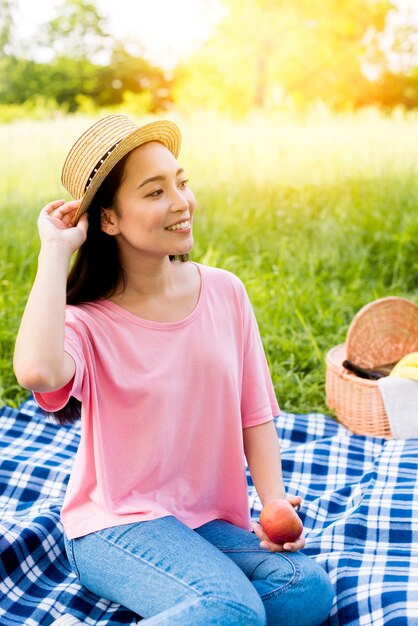 Asian woman with apple sitting on cloth