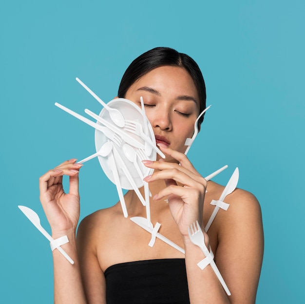 Asian woman with closed eyes being covered in white plastic tableware