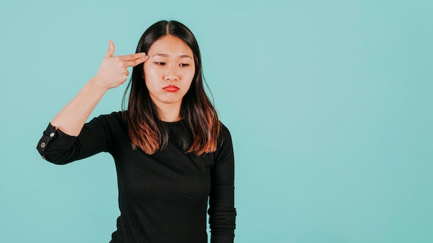 Asian woman with finger gun near head