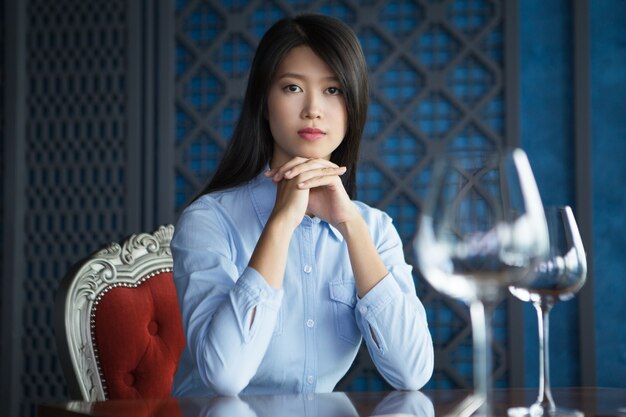 Asian Woman with Hands under Chin in Restaurant