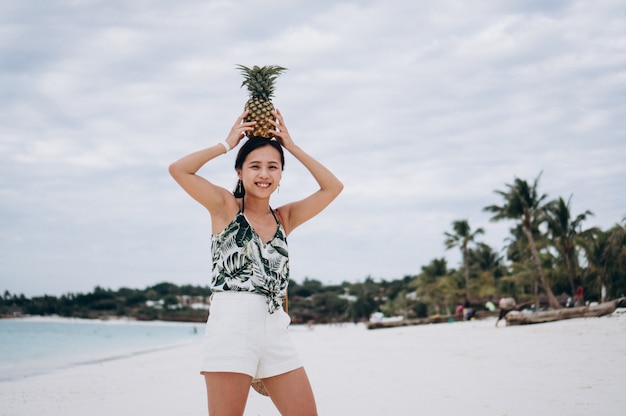 Бесплатное фото Азиатская женщина с ананасом на пляже