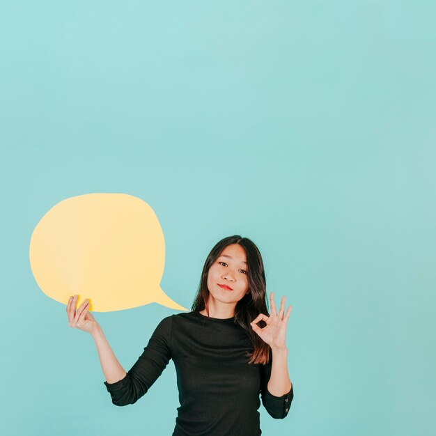 Asian woman with speech bubble gesturing OK