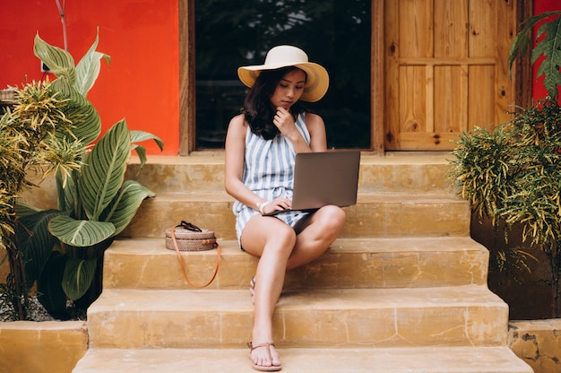 Asian woman working on laptop on a vacation and sitting on the stairs