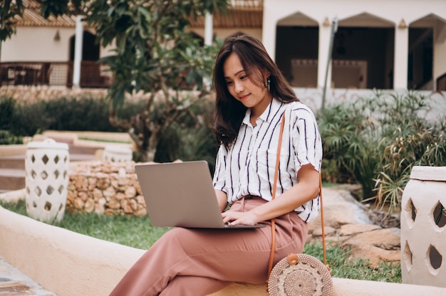 Free photo asian woman working on laptop on a vacation