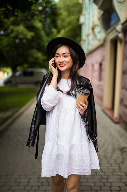 도시 거리를 이야기하는 아시아 womanwith 모자와 선글라스 휴대 전화