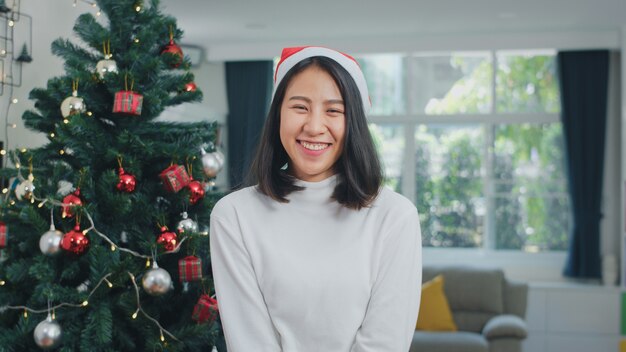 Asian women celebrate Christmas festival. Female teen wear Christmas hat relax happy smiling looking enjoy xmas winter holidays together in living room at home.