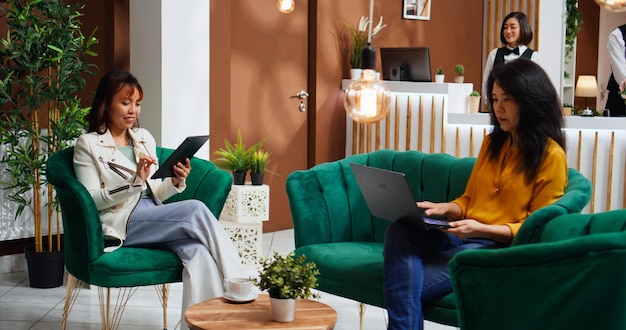 Free photo asian women passing time in lounge area at hotel