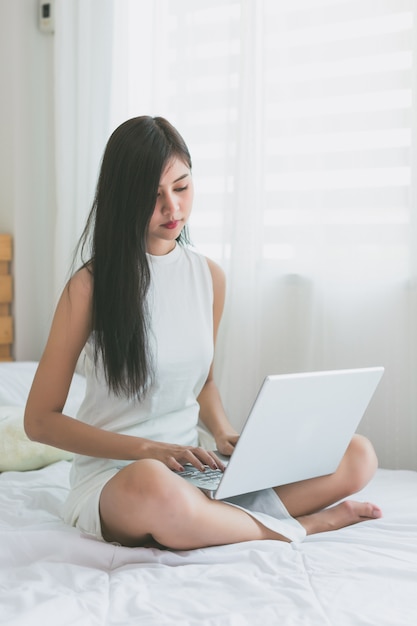 Asian women play with laptop in the bedroom