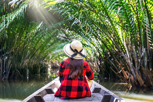 タイ、スラートターニーのニッパヤシやヤシの木からトンネルでボートに座っているアジアの女性。