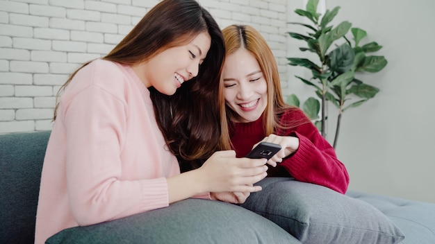 Азиатские женщины с помощью смартфона, проверка социальных медиа в гостиной дома