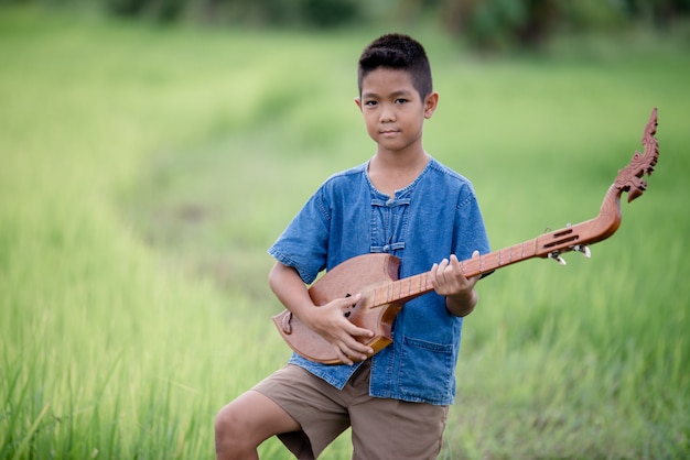 Asian young boy with guitar handmade in the outdoor, Life country