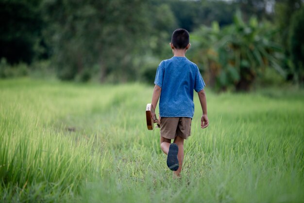 Asian young boy with guitar handmade in the outdoor, Life country