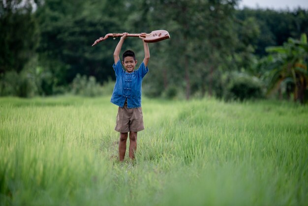 Asian young boy with guitar handmade in the outdoor, Life country