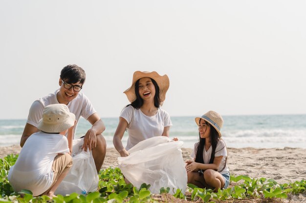 해변에서 플라스틱 폐기물을 수집하는 아시아 젊은 행복한 가족 운동가. 아시아 자원 봉사자들은 자연을 깨끗하게 유지하고 쓰레기를 줍도록 도와줍니다. 환경 보전 오염 문제에 대한 개념.