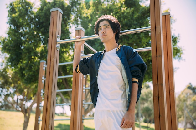 Free photo asian young man standing by monkey bars