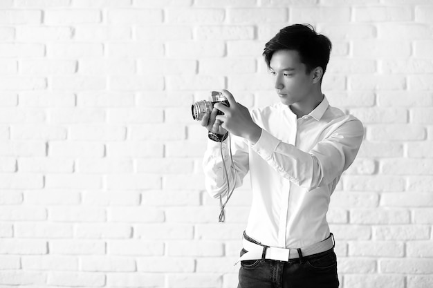 アジアの若い男はスタジオでカメラを使用します