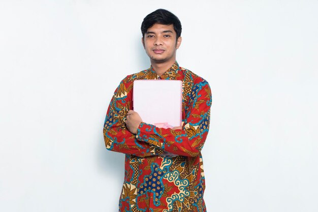 Asian young man wearing batik confident while holding a pink envelope isolated on white background