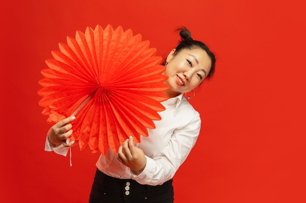 Азиатская молодая женщина, держащая большой фонарь на красной стене