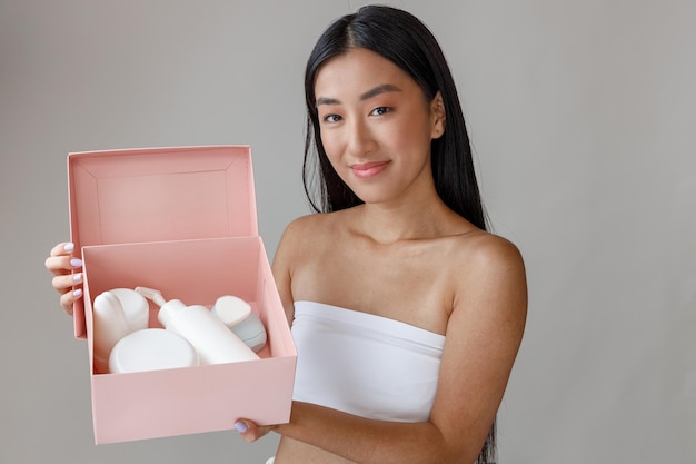 Азиатская молодая женщина держит коробку с косметическими продуктами Premium Фотографии